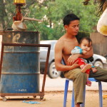 Family hanging out at gas station in Cambodia