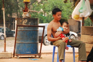 Family hanging out at gas station in Cambodia